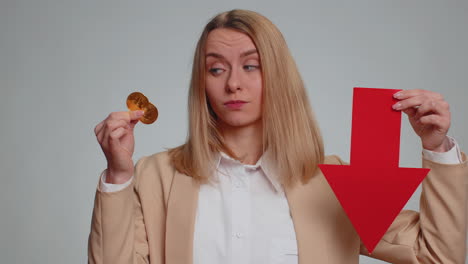 woman holding bitcoin and a red arrow pointing down