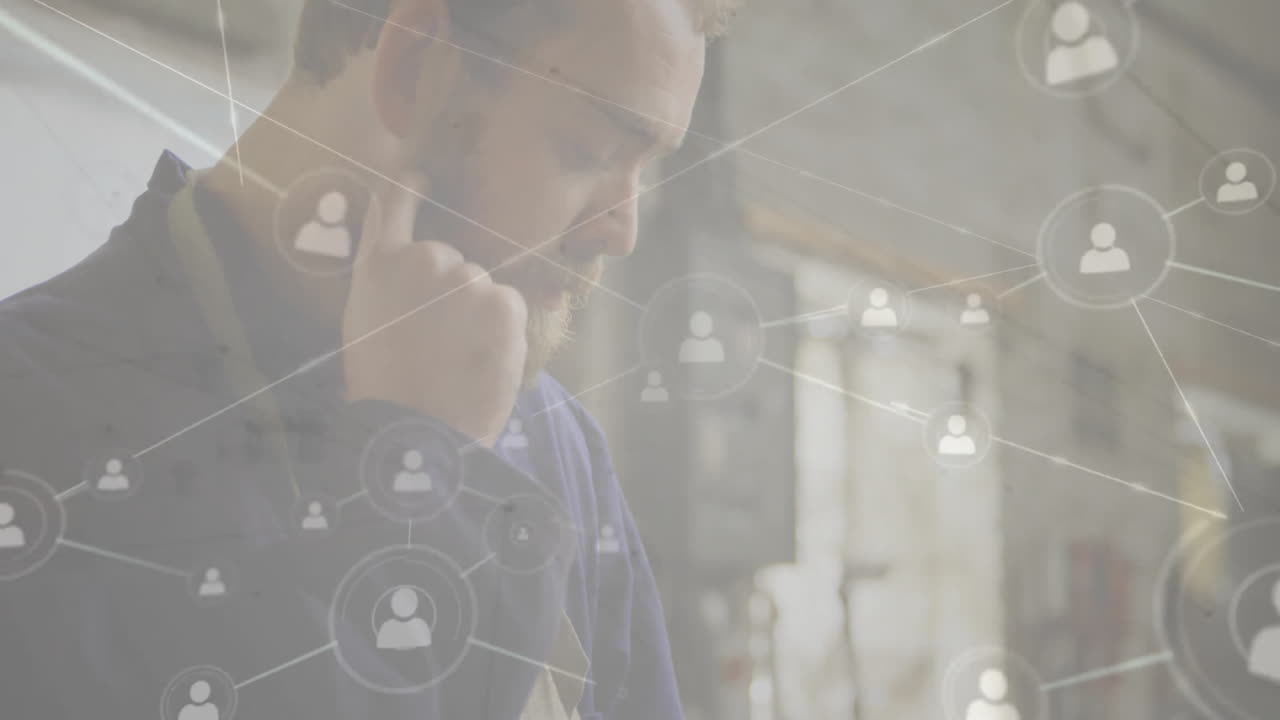 Male craftsman holding smartphone to ear in workshop, showing animated tech user profile network