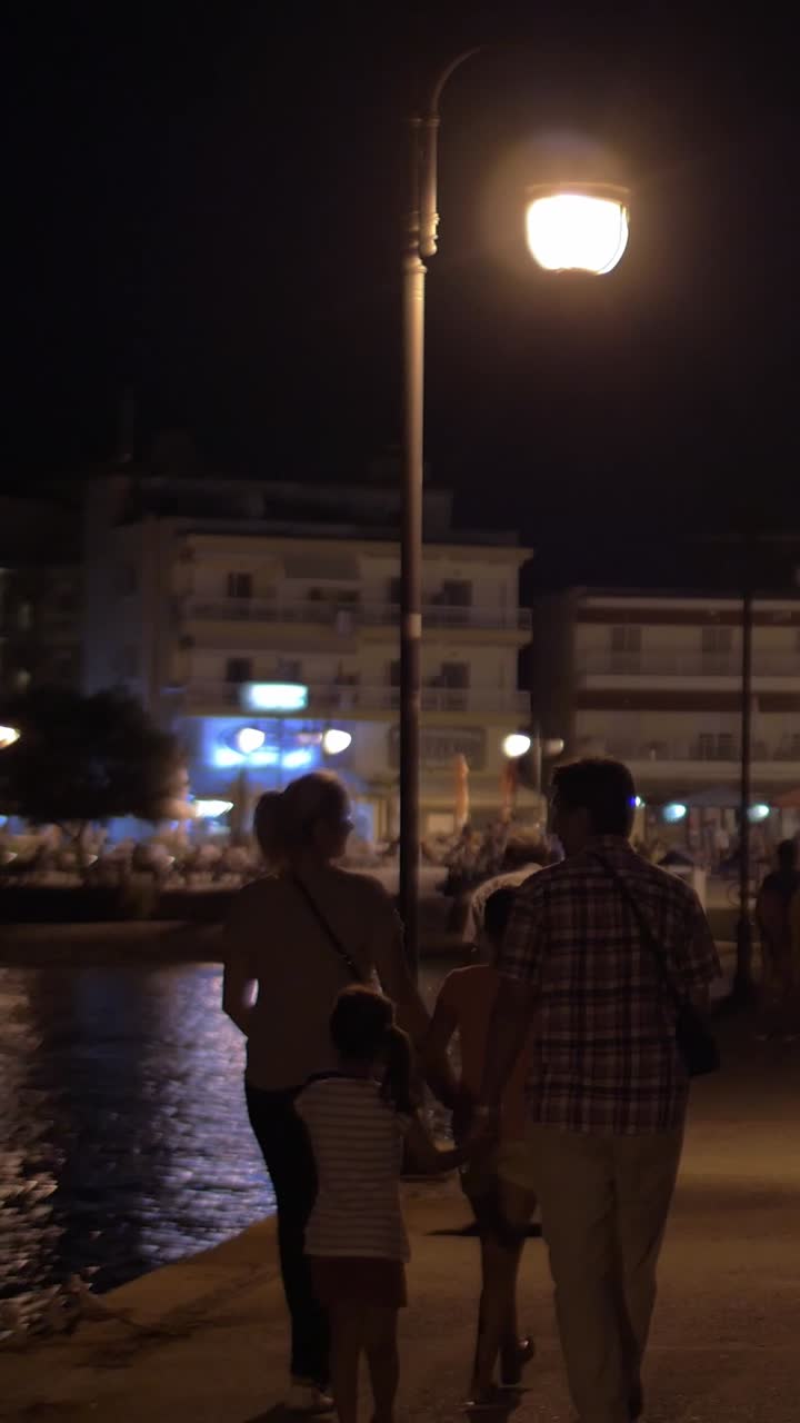 Night scene with people near water and buildings