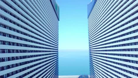 the drone flies between two buildings with glass windows.