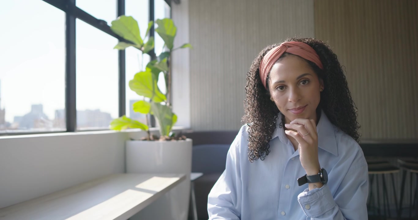 Donna afroamericana che usa il tablet in ufficio, prende il telefono, controlla il lavoro, con spazio per il testo.
