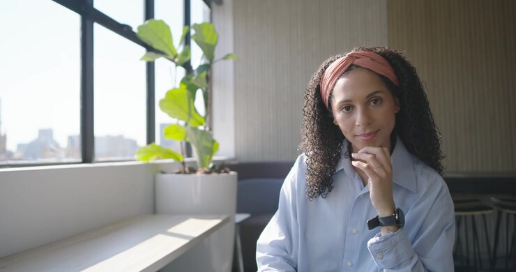 Donna afroamericana che usa il tablet in ufficio, prende il telefono, controlla il lavoro, con spazio per il testo.