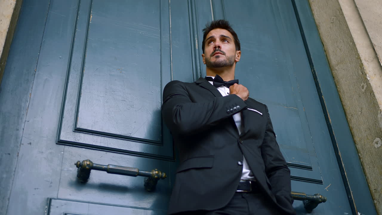 파란 문 근처에 검은 스모킹을 입은 남자