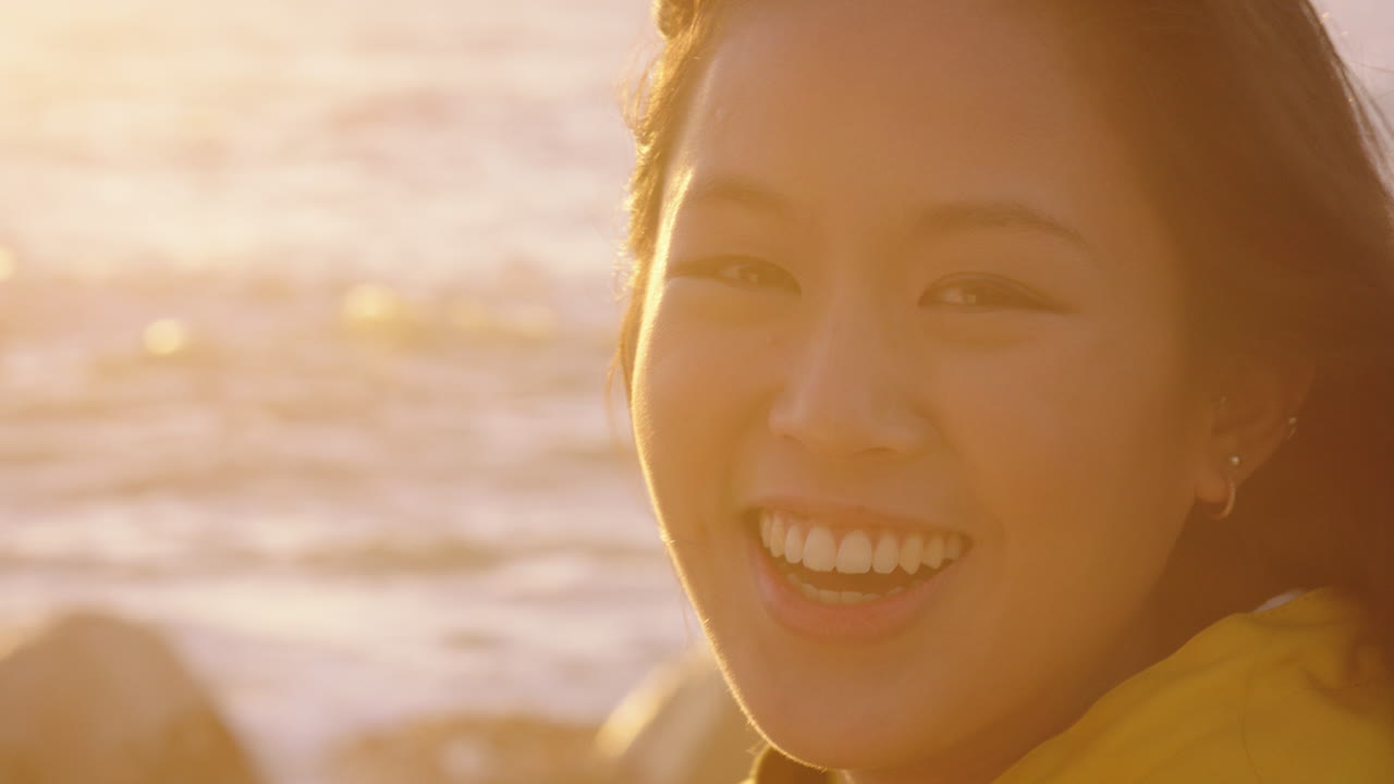 행복한 아시아 여성의 초상화 웃음 휴가를 즐기고 여행 라이프 스타일을 탐험 해변에서 휴식을 취하고 바람이 불고 있는 머리카락으로 일몰에 긍정적 인 느낌