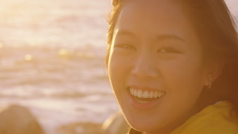 Porträt-Einer-Glücklichen-Asiatischen-Frau,-Die-Lacht-Und-Den-Urlaub-Genießt,-Den-Reiselebensstil-Erkundet,-Sich-Am-Strand-Entspannt-Und-Sich-Bei-Sonnenuntergang-Mit-Windigen-Haaren-Positiv-Fühlt