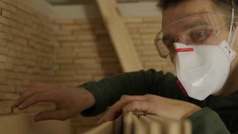 woodworker professional in mask and glasses checks wood raw, wooden plank, plywood panel