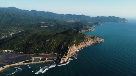 Mountain-landscape-with-rocky-seaside-cliffs-and-small-sandy-beach-in-Vietnam