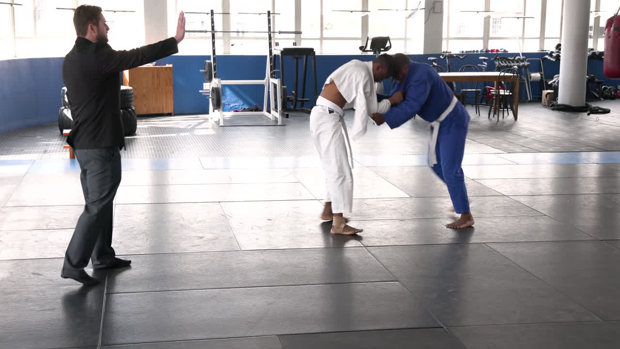 Practicing judo, men in martial arts uniforms training in gym with coach