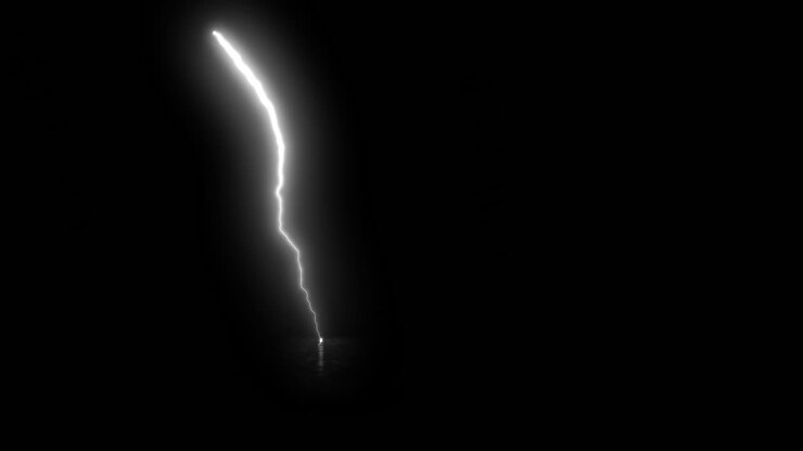 Effetto luminoso di fulmine che colpisce il terreno con sfondo nero.