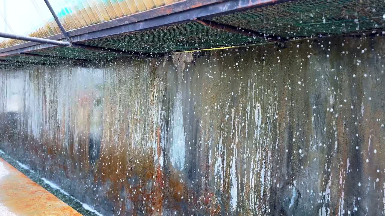 A detailed 4K video of water dripping from a roof onto a weathered concrete wall, forming natural streaks and textures. Perfect for backgrounds, transitions, or relaxation content.