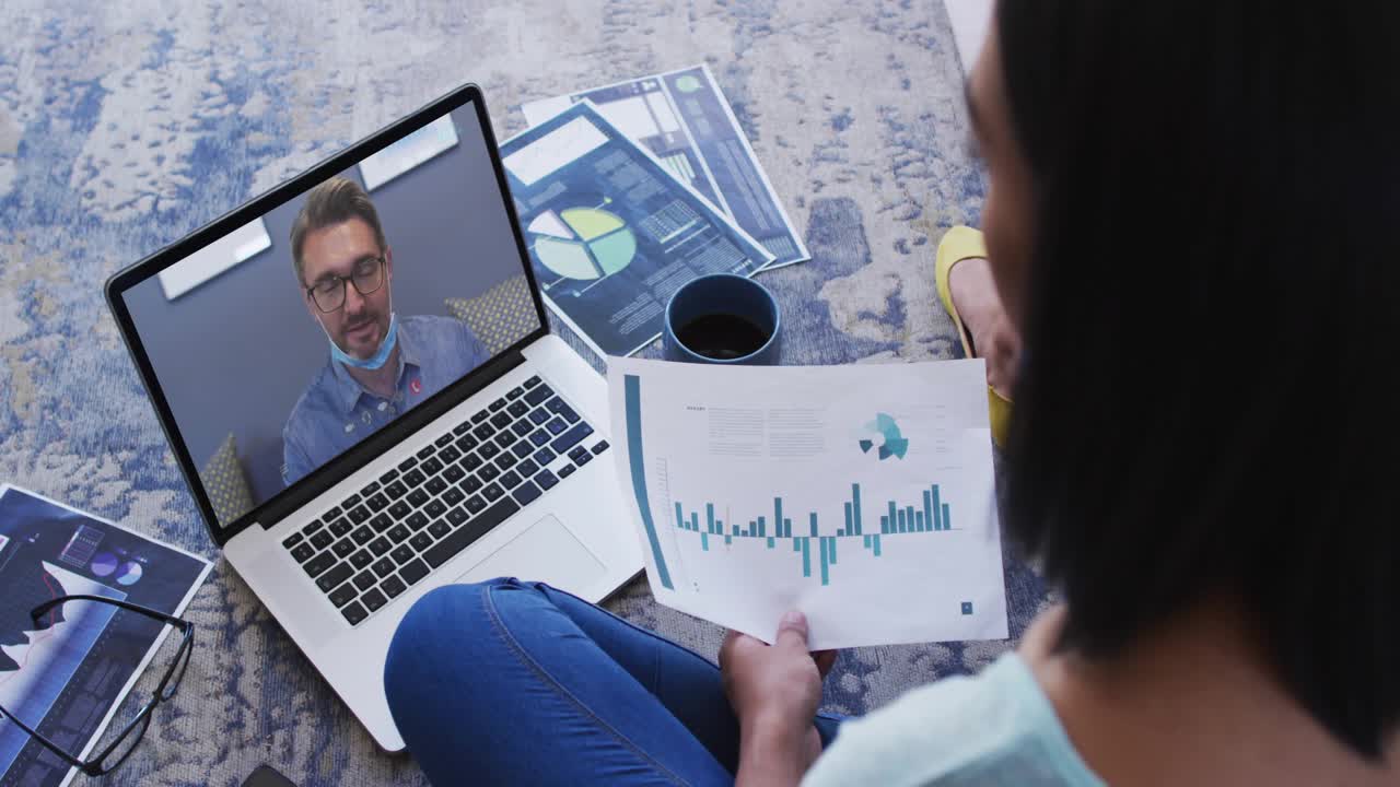 Seated woman reading chart during work call, man speaking as social icons rising over laptop, chart
