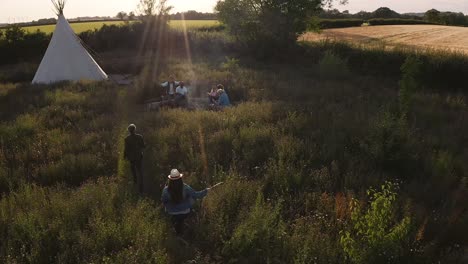 drone shot of two mature women camping in teepee in field meeting with friends