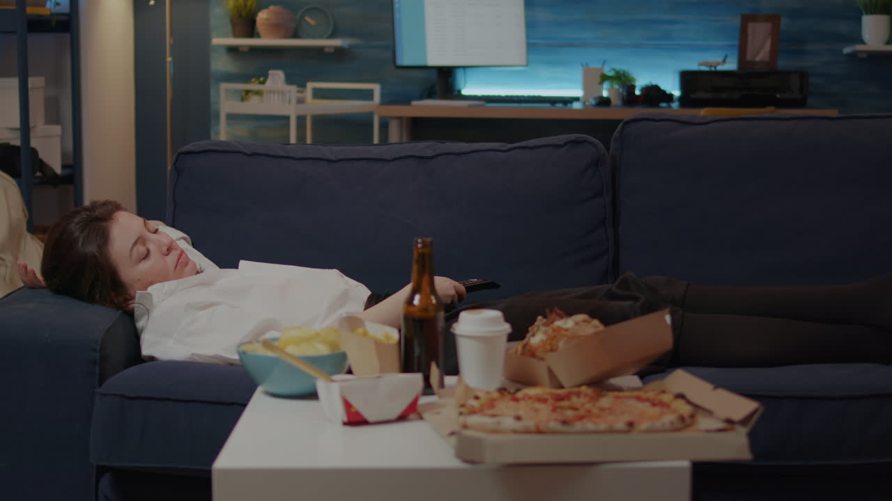 Sleepy adult relaxing on sofa after eating takeaway meal