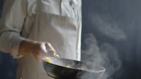 close up of unrecognizable chef tossing chopped vegetables from a pan