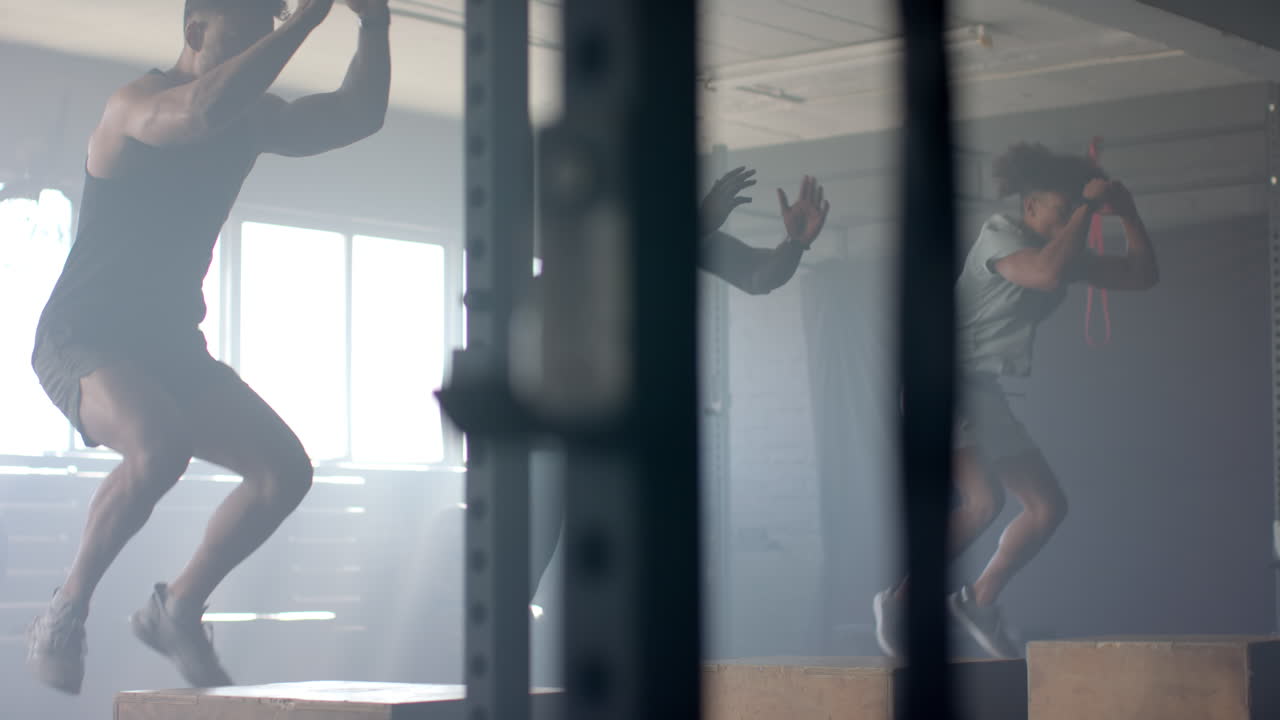 Exercising in gym, men performing box jumps and strength training workout