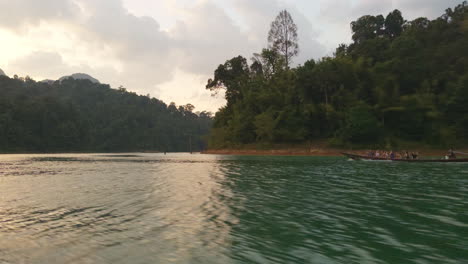 Longtail-Boot-Segelt-Auf-Dem-Smaragdgrünen-Wasser-Von-Koh-Phi-Phi,-Thailand-Bei-Sonnenuntergang-Mit-Wunderschönen-Spiegelungen-Auf-Der-Oberfläche