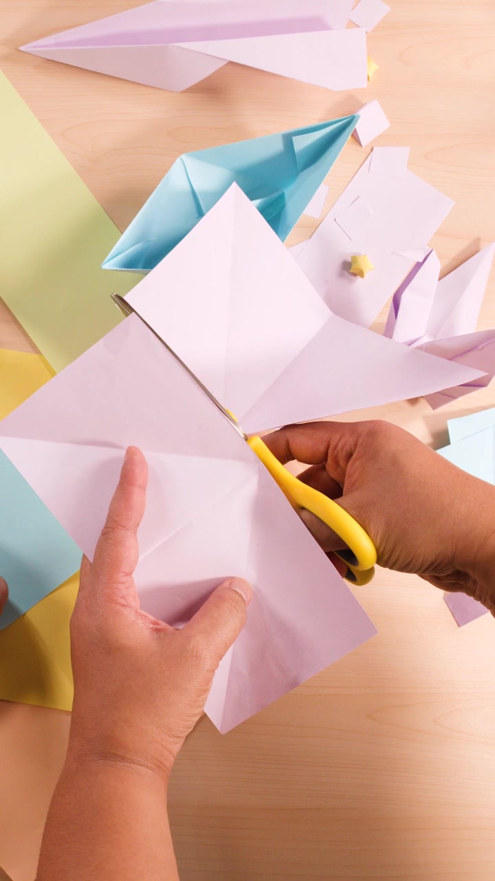 Vista dall'alto di mani che usano le forbici e piegano la carta per vari progetti di artigianato origami.