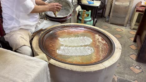 A-local-people-pastry-making-workshop-make-rice-liquid-thread-on-a-fry-pan-for-sweet-dessert-with-walnut-and-cinnamon-roll-confectionary-product-to-sell-in-local-market-food-cullinary-cuisine-ramadan