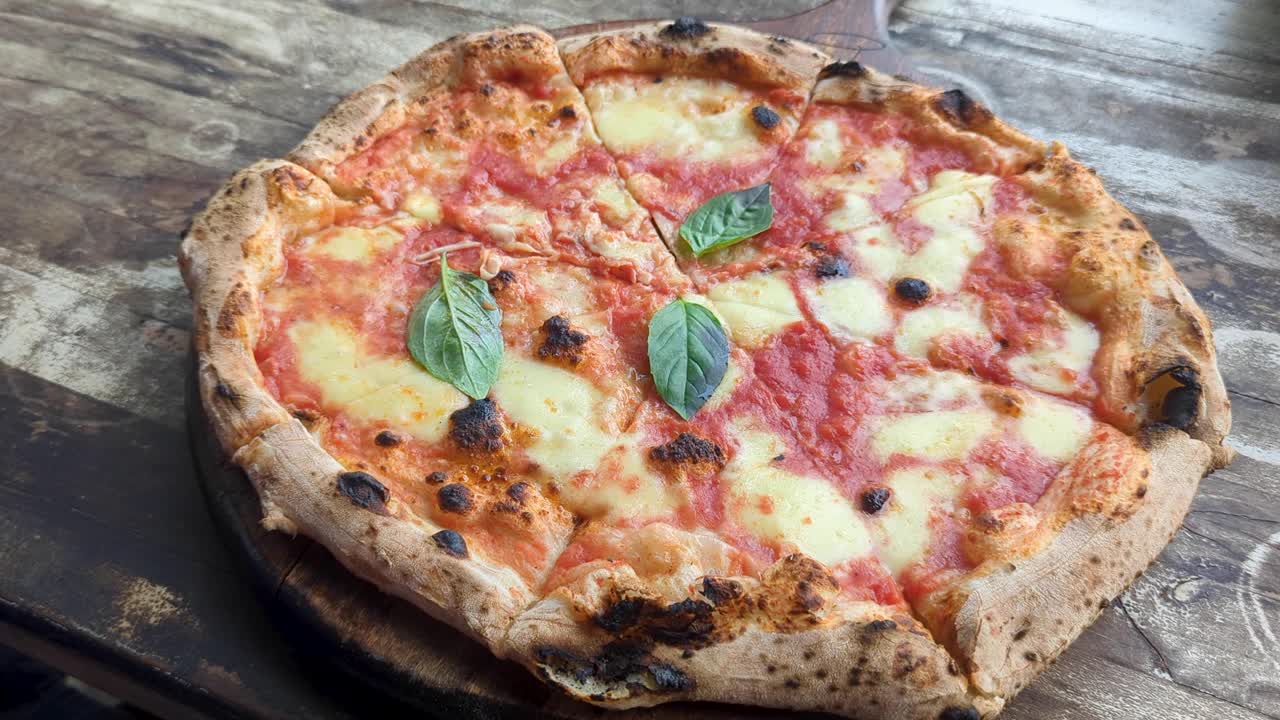 Taking a slice of homemade traditional Italian wood fired Margherita pizza presented on rustic wooden table top