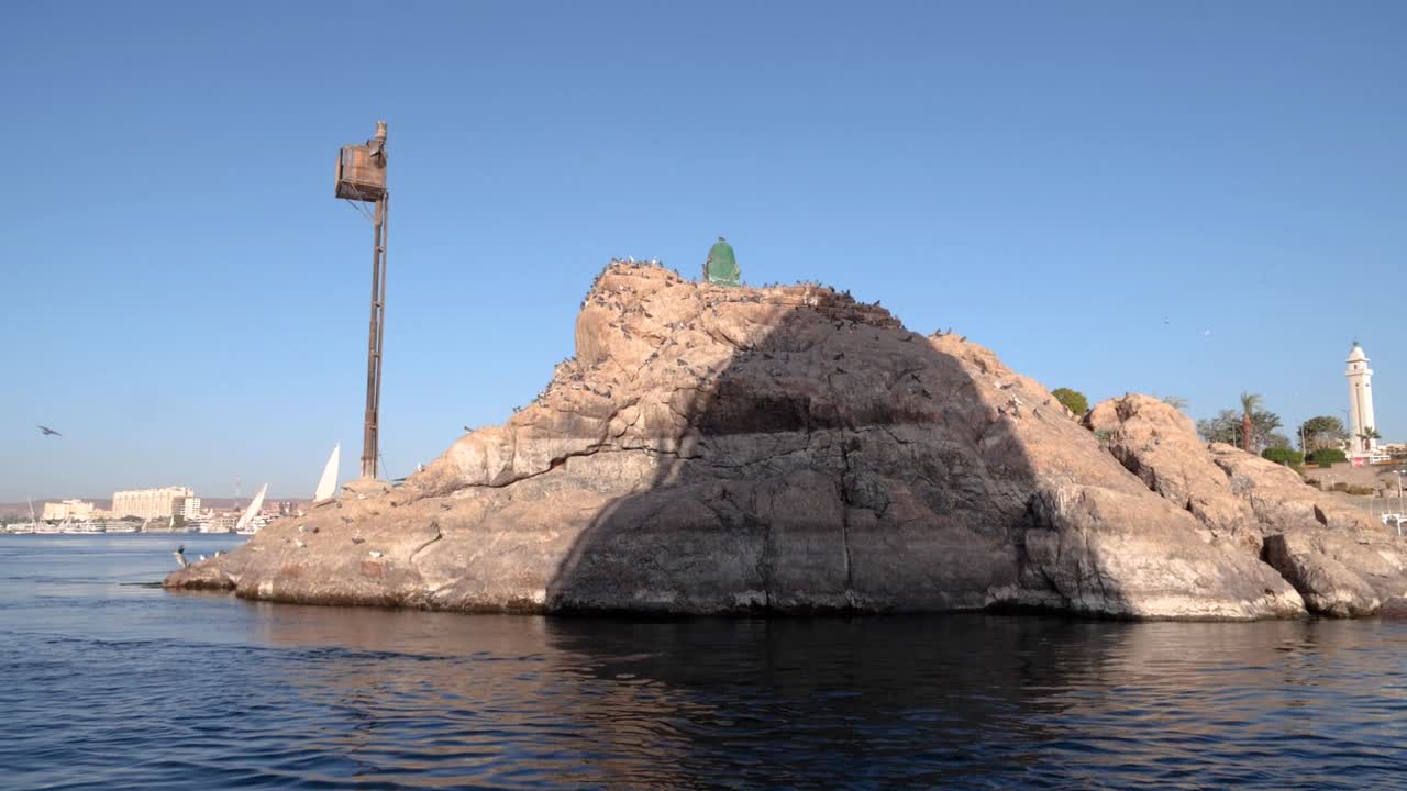 나일 강, 아스완, 이집트에 있는 새 비둘기가 있는 바위에 있는 펠루카의 그림자의 넓은 전망