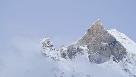 dramatic mountain top in clouds in nepal, high snowy snowcapped winter himalayas mountains summit covered in snow, atmospheric beautiful jagged rugged mountain peaks close up