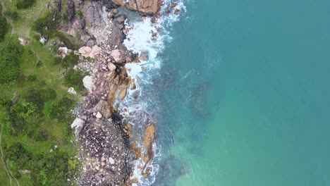 Aerial-Top-View-Drone-Footage-of-Ocean-Waves-Reaching-Green-Shore