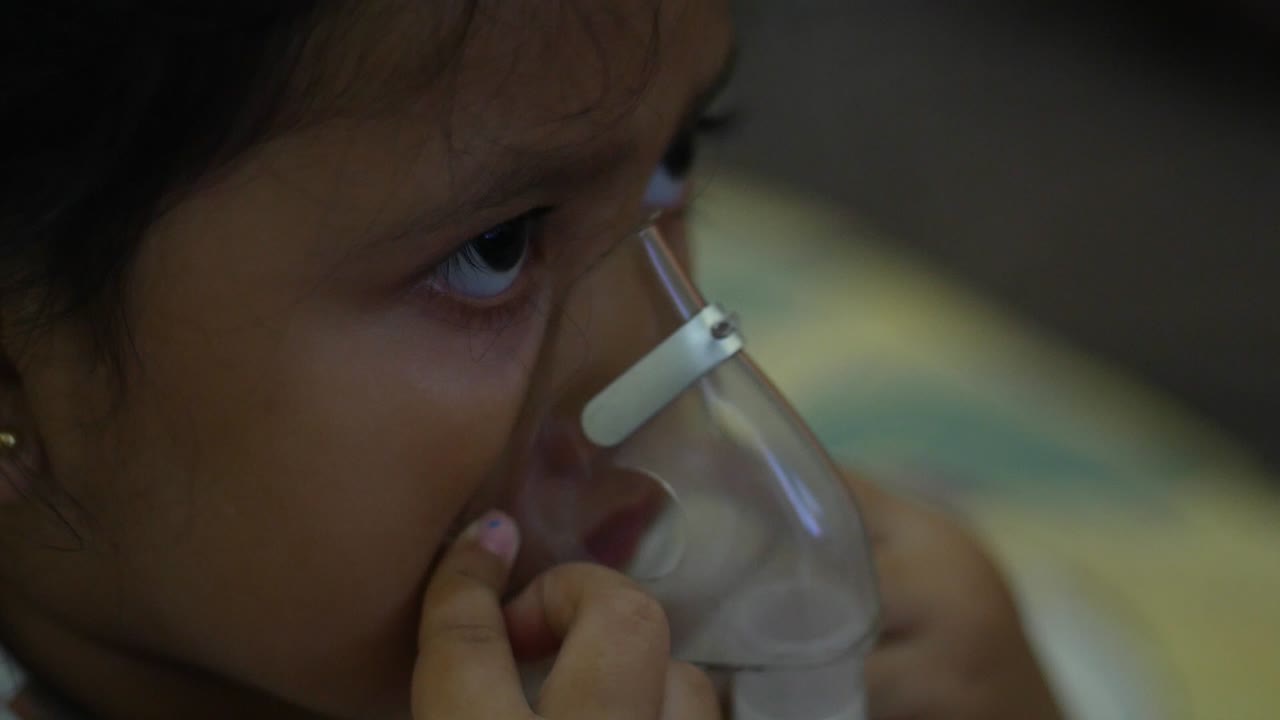 Beautiful sick girl has inhalation therapy, uses portable nebulizer, holds mask vapor at home. Respiratory disease. Health concept