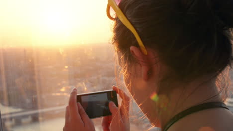 turista tomando una fotografía de la puesta de sol en el horizonte de londres vista desde el fragmento