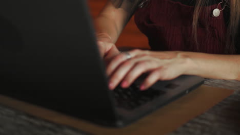 Close-up-young-woman-wearing-smartwatch-using-laptop-computer.-Female-working-on-laptop-in-an-outdoor-cafe.