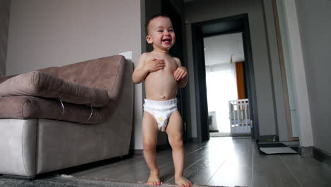 cute happy caucasian boy running about the house. baby in diaper playing at home. low angle view.