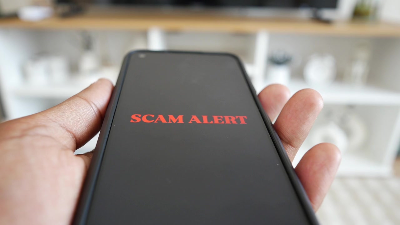 Hand Holding Smartphone Displaying Scam Alert Warning