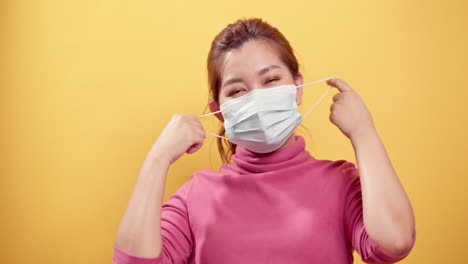 젊은 아시아 여성은 civid-19 상황이 노란색 배경으로 풀린 후 행복하고 웃고 신선한 공기를 위해 보호 마스크를 벗고 있습니다.