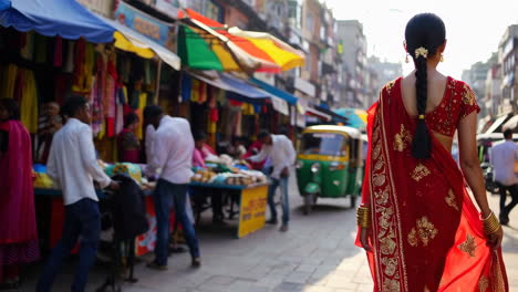 woman in saree walking through a bustling indian market