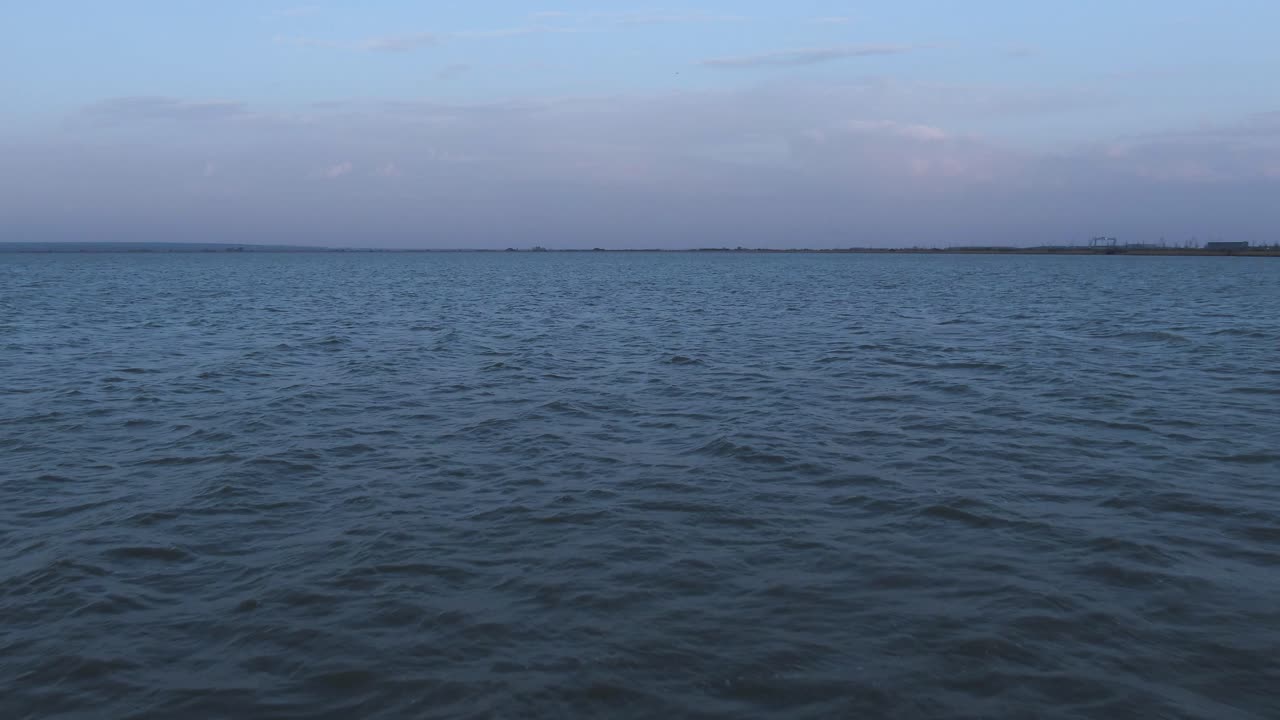 Flying towards the horizon line than rising over a big lake on a windy cold day, drone shot, desolated