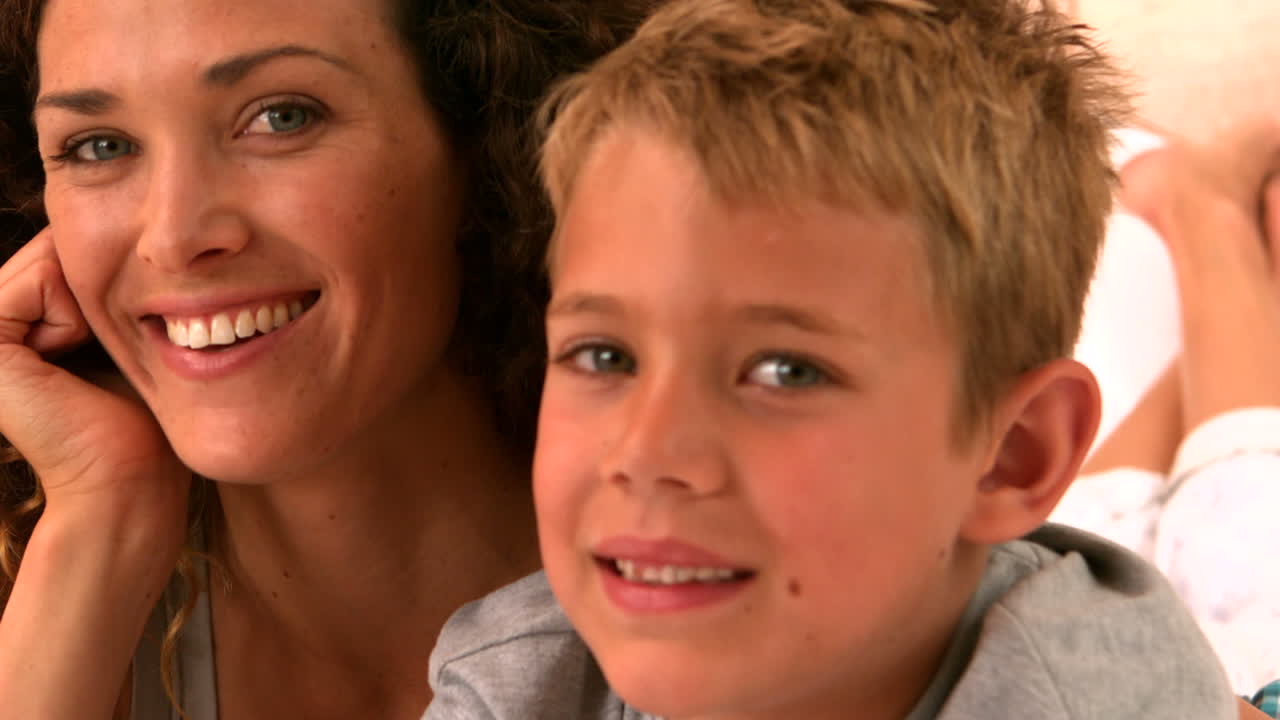 Vídeo Premium - Madre e hijo acostados en la cama sonriendo a la cámara