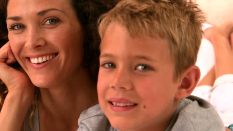 madre e hijo acostados en la cama sonriendo a la cámara