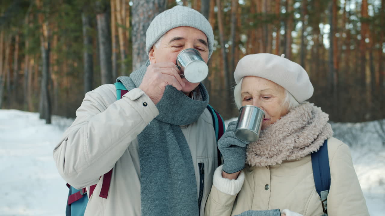 Senior Couple Enjoying a Hot Drink in Winter Forest