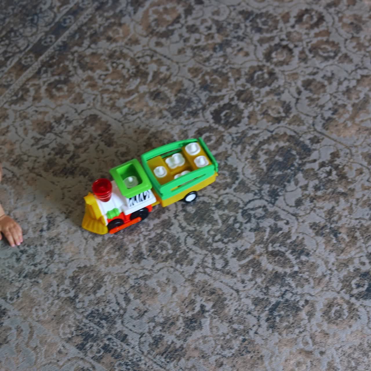 Active dark-haired toddler crawls by the carpet. Kid plays with a toy car. Top view