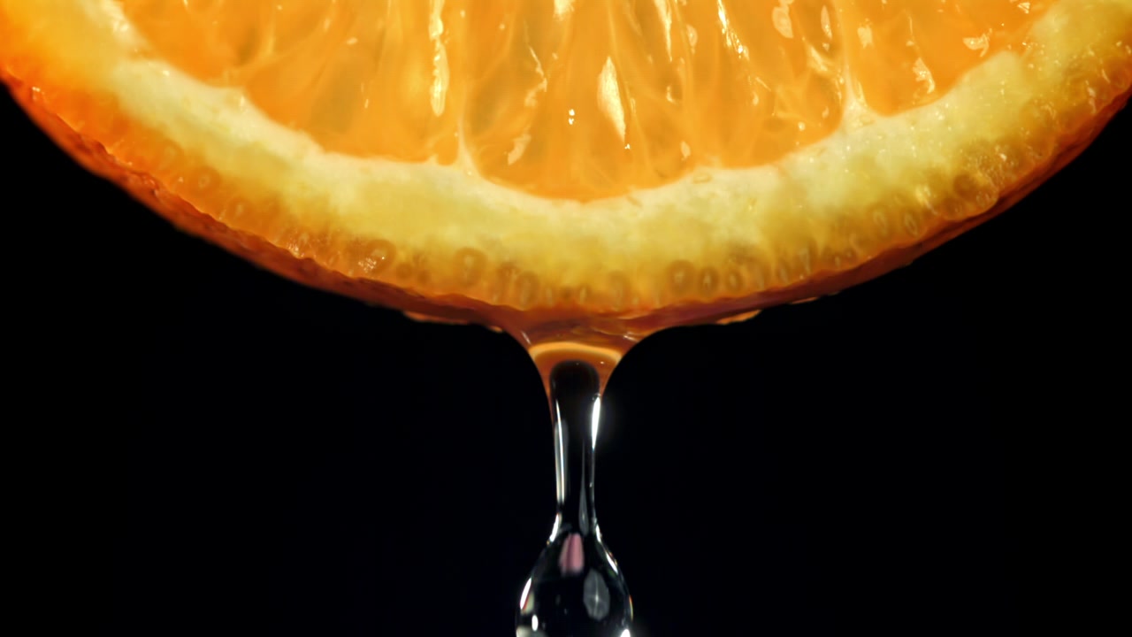 Ripresa macro di una fetta d'arancia con una goccia di succo che cade