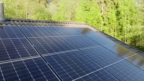 Drone-rotating-over-partly-shadowed-solar-panels-on-a-house-roof,-summer-evening