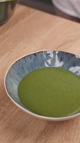 chef pouring spinach soup into a bowl