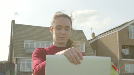 Female-opens-up-her-laptop-to-work-outside-in-a-park