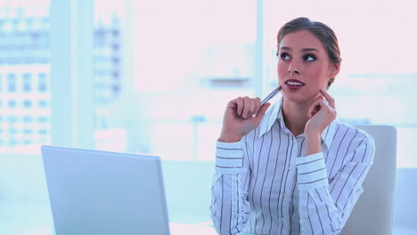 una mujer de negocios pensativa tomando notas.
