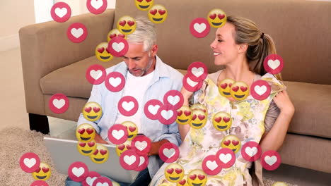 animación de iconos de amor sobre pareja caucásica pagando con tarjeta de crédito usando una computadora portátil.