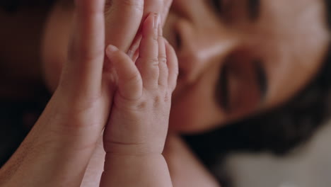 de cerca madre feliz sosteniendo al bebé con la mano tocando los dedos cuidando al recién nacido cuidando al bebé disfrutando de la conexión de la maternidad con el niño