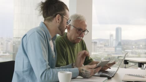 a young hipster educator is teaching a senior male student how to design a website in the classroom.