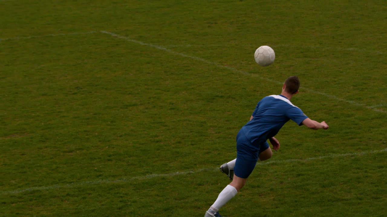 Football player in blue kicking the ball on pitch
