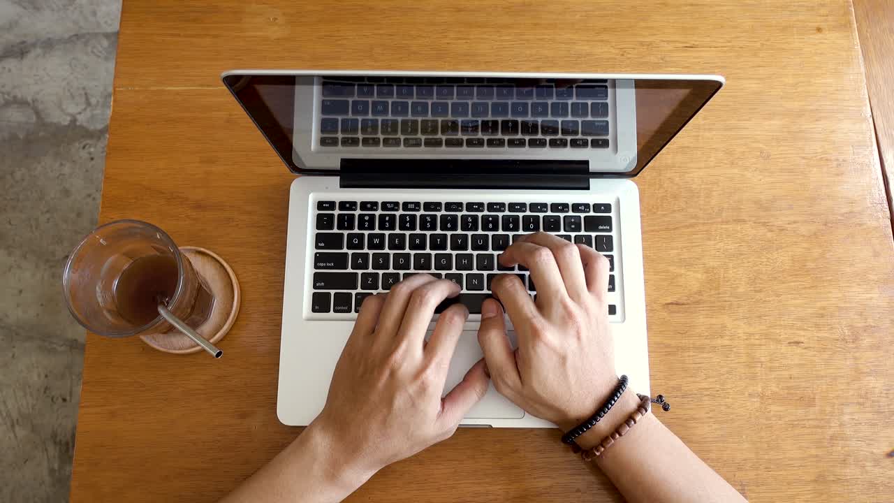Static top view of young hip millennial working on his laptop in a coffee place