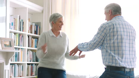 happy senior couple dance in their living room