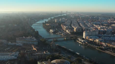 aerial view of seville, spain on sunny afternoon, river canal and cityscape, drone shot